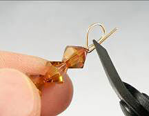 Bicone beads on a head pin being bent with pliers